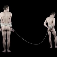 Two male nudes, one tied up, one holding the string